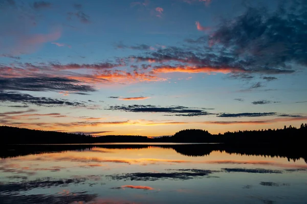 Geniş açı güzel akşam manzarası ağaçların silueti ve günbatımı gökyüzü ile su üzerinde
