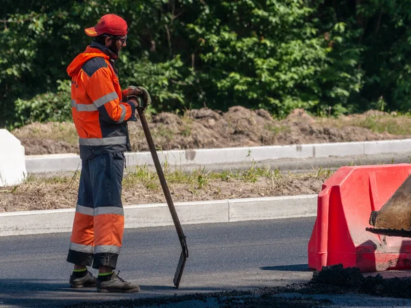 Petrozavodsk, Rusya - 21 Haziran 2020. Üniformalı yol işçisi elinde küreği incelikle tutuyor.