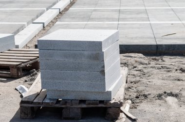 Paletin üzerine asfalt yığılmış. kaldırım levhalarıyla yayaları döşüyorlar.