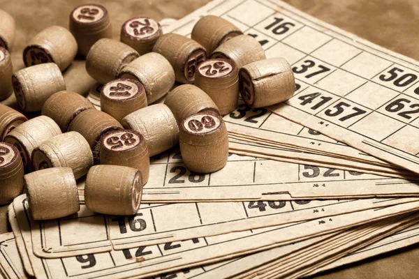 Table game Bingo. Wooden Lotto barrels with bag, playing cards for Lotto game, game for family on brown background