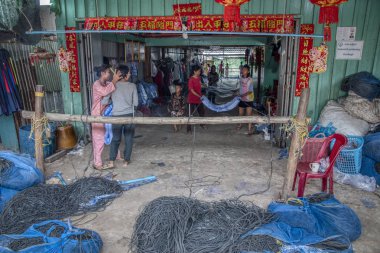 Sihanoukville, Kamboçya. 26 Şubat 2019: Sihanoukville Balıkçı Köyü'nde bulunan ahşap dükkanında bir grup genç kız ve anne balık ağı yapmak veya örmek.