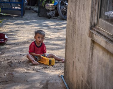 Sihanoukville, Kamboçya. 25 Şubat 2019 : Sihanoukville balıkçı Köyü'ndeki evinin yanındaki kumda tek başına oynayan küçük çocuk sahnesi.