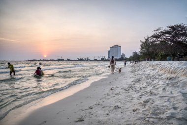 Sihanoukville, Kamboçya - 26 Şubat 2019: Krong Vaaz Sihanouk plajında eğlenirken deniz kıyısında oynanan çocuklar gibi aileler ve arkadaşlarla birlikte güzel gün batımını izleyen insanlar