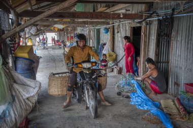 Sihanoukville, Kamboçya. 26 Şubat 2019: Sihanoukville Balıkçı Köyü'ndeki ahşap evinin önünde balıkçıağı tamir eden balıkçının sahnesi. 