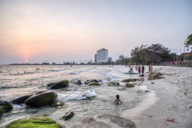 Sihanoukville, Kamboçya - 26 Şubat 2019: Krong Vaaz Sihanouk plajında eğlenirken deniz kıyısında oynanan çocuklar gibi aileler ve arkadaşlarla birlikte güzel gün batımını izleyen insanlar