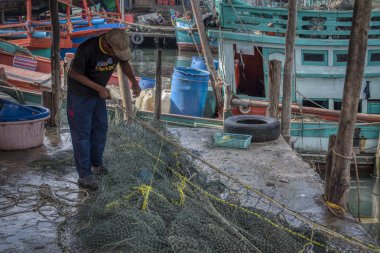 Sihanoukville, Kamboçya. 26 Şubat 2019: Sihanoukville Balıkçı Köyü'nde teknesinin bulunduğu rıhtımda balıkçı ağını tamir eden balıkçının sahnesi. 