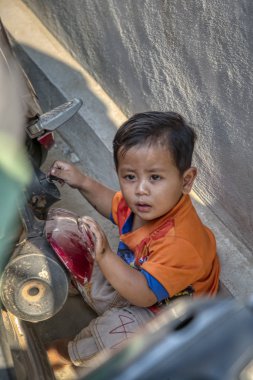Sihanoukville, Kamboçya. 25 Şubat 2019 : Sihanoukville balıkçı Köyü'nde ana koridorunun yanında motosikletle oynayan küçük çocuğun sahnesi.