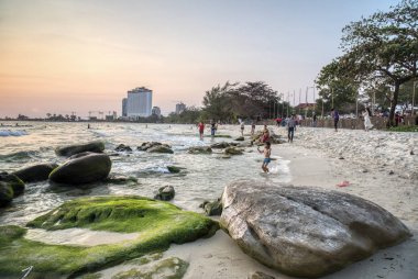 Sihanoukville, Kamboçya - 26 Şubat 2019: Krong Vaaz Sihanouk plajında eğlenirken deniz kıyısında oynanan çocuklar gibi aileler ve arkadaşlarla birlikte güzel gün batımını izleyen insanlar