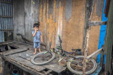 Sihanoukville, Kamboçya. 25 Şubat 2019 : Sihanoukville balıkçı Köyü'ndeki evinde bisikletinin yanında duran genç çocuğun sahnesi.