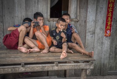 Sihanoukville, Kamboçya. 26 Şubat 2019: Sihanoukville Balıkçı Köyü'nde ziyaretçiler yollarını geçerken çocuklar utangaç ve aynı zamanda bankta yaramazlık yapıyor.