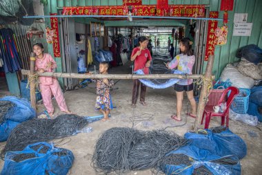 Sihanoukville, Kamboçya. 26 Şubat 2019: Sihanoukville Balıkçı Köyü'nde bulunan ahşap dükkanında bir grup genç kız ve anne balık ağı yapmak veya örmek.