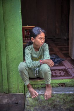 Sihanoukville, Kamboçya. Şubat 25,2019 : Sihanoukville balıkçı Köyü'nde evinin kapısının önünde birini bekleyen ciddi bir bakışla kız sahnesi. 