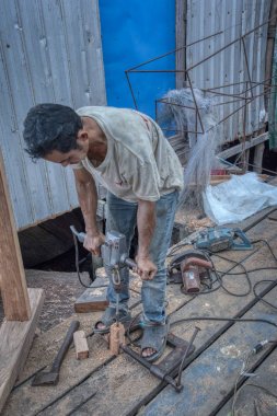 Sihanoukville, Kamboçya. 26 Şubat 2019 : Marangoz, Sihanoukville Balıkçı Köyü'nde tekneyi tamir etmek için yaptığı aletlerle ahşap işleri yapmakla meşgul.