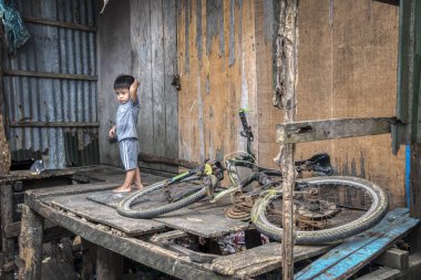 Sihanoukville, Kamboçya. 25 Şubat 2019 : Sihanoukville balıkçı Köyü'ndeki evinde bisikletinin yanında duran genç çocuğun sahnesi.