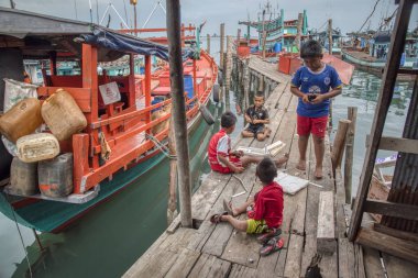 Sihanoukville, Kamboçya. 25 Şubat 2019 : Sihanoukville balıkçı limanındaki ahşap iskelenin rıhtımında oynayan çocuklar balıkçı köyüsahnesi.