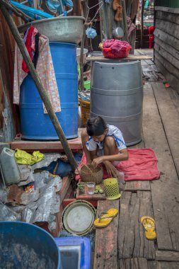 Sihanoukville, Kamboçya. 25 Şubat 2019: Sihanoukville balıkçı köyündeki ahşap evinde açık yıkama alanında aşçılık oynayan kız sahnesi.