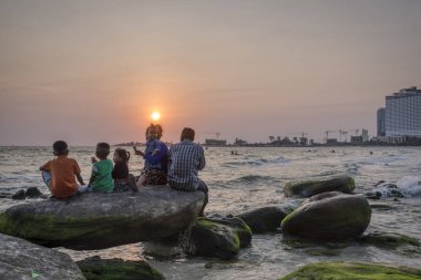 Sihanoukville, Kamboçya - 26 Şubat 2019: Krong Vaaz Sihanouk plajında eğlenirken deniz kıyısında oynanan çocuklar gibi aileler ve arkadaşlarla birlikte güzel gün batımını izleyen insanlar