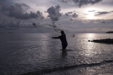 Perak, Malezya.7 Mayıs 2019: Tanjung Sepah plajında karides yakalamaya çalışan yüksek gelgit sırasında deniz kenarında duran Malay adam denize ağ dökme, Lekir.