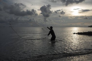 Perak, Malezya.7 Mayıs 2019: Tanjung Sepah plajında karides yakalamaya çalışan yüksek gelgit sırasında deniz kenarında duran Malay adam denize ağ dökme, Lekir.