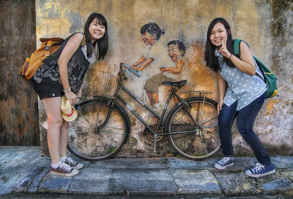 İki Çinli genç kız Penang duvar sanatı boyama sokakta mutlu poz, Georgetown.