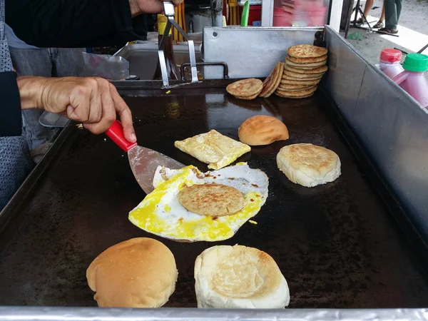 someone unrecognized preparing meat and egg burger