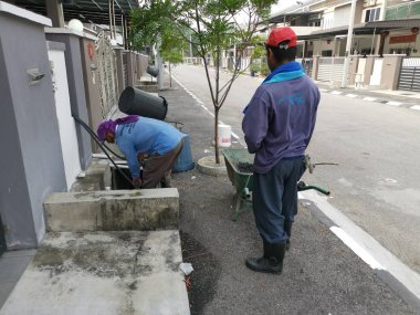 Perak, Malezya. 24 Ağustos 2019: Taman Pelangi Kampong Koh'daki yerleşim bölgesinin drenaj sistemini temizleyen iki Hintli belediye işçisinin sahnesi. 