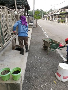 Perak, Malezya. 24 Ağustos 2019: Taman Pelangi Kampong Koh'daki yerleşim bölgesinin drenaj sistemini temizleyen iki Hintli belediye işçisinin sahnesi. 
