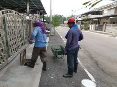 Perak, Malezya. 24 Ağustos 2019: Taman Pelangi Kampong Koh'daki yerleşim bölgesinin drenaj sistemini temizleyen iki Hintli belediye işçisinin sahnesi. 