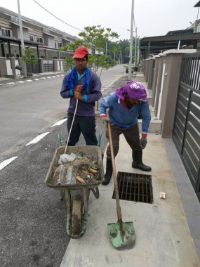 Perak, Malezya. 24 Ağustos 2019: Taman Pelangi Kampong Koh'daki yerleşim bölgesinin drenaj sistemini temizleyen iki Hintli belediye işçisinin sahnesi. 