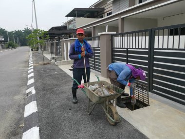 Perak, Malezya. 24 Ağustos 2019: Taman Pelangi Kampong Koh'daki yerleşim bölgesinin drenaj sistemini temizleyen iki Hintli belediye işçisinin sahnesi. 