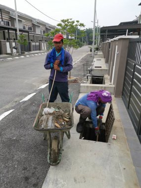 Perak, Malezya. 24 Ağustos 2019: Taman Pelangi Kampong Koh'daki yerleşim bölgesinin drenaj sistemini temizleyen iki Hintli belediye işçisinin sahnesi. 