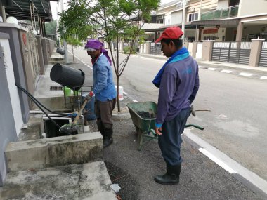 Perak, Malezya. 24 Ağustos 2019: Taman Pelangi Kampong Koh'daki yerleşim bölgesinin drenaj sistemini temizleyen iki Hintli belediye işçisinin sahnesi. 
