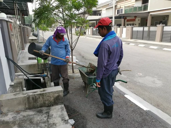 Perak, Malezya. 24 Ağustos 2019: Taman Pelangi Kampong Koh'daki yerleşim bölgesinin drenaj sistemini temizleyen iki Hintli belediye işçisinin sahnesi. 