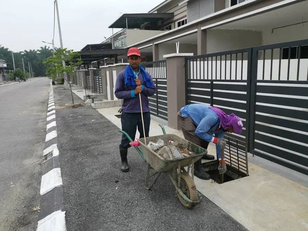 Perak, Malezya. 24 Ağustos 2019: Taman Pelangi Kampong Koh'daki yerleşim bölgesinin drenaj sistemini temizleyen iki Hintli belediye işçisinin sahnesi. 