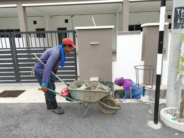 Perak, Malezya. 24 Ağustos 2019: Taman Pelangi Kampong Koh'daki yerleşim bölgesinin drenaj sistemini temizleyen iki Hintli belediye işçisinin sahnesi. 