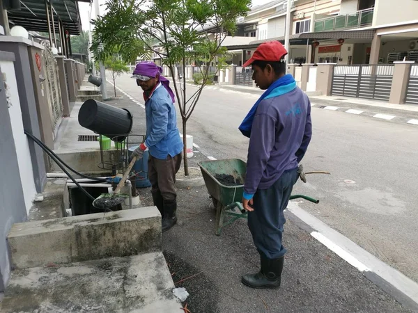 Perak, Malezya. 24 Ağustos 2019: Taman Pelangi Kampong Koh'daki yerleşim bölgesinin drenaj sistemini temizleyen iki Hintli belediye işçisinin sahnesi. 