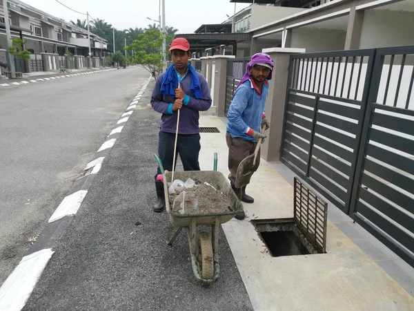 Perak, Malezya. 24 Ağustos 2019: Taman Pelangi Kampong Koh'daki yerleşim bölgesinin drenaj sistemini temizleyen iki Hintli belediye işçisinin sahnesi. 