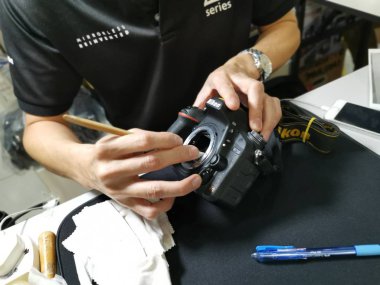 Perak, Malezya. 4 Ekim 2019: Aeon Sri Manjung Alışveriş Merkezi 'nde bulunan N4 Kamera Mağazası' nda Nikon kullanıcıları ve fotoğrafçıları için teknisyen temizlik DSR vücut sensörü ve lens.