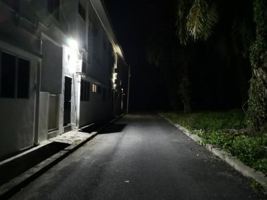 Karanlık kaldırımı aydınlatan sokak lambaları.