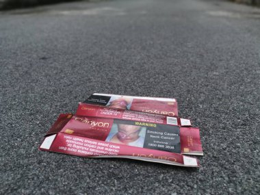 Perak, Malezya. 16 Ağustos 2020: Jalan Godi Caddesi, Kg Koh 'ta asfalt yolun ortasına atılmış kırmızı boş bir sigara kutusu sahnesi.