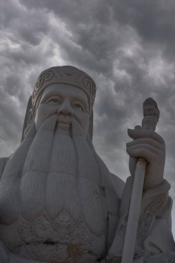 Gökyüzü manzaralı ve ön planda Çin mitolojisi tanrıları heykeli var.