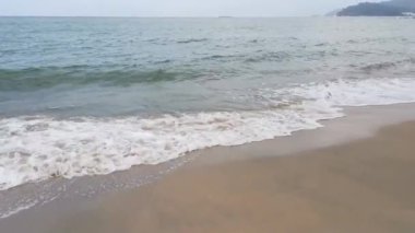 Gündüz sahnesi deniz yükseldiğinde kumlu kumsalda dalgalar hareket ederken