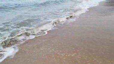 Gündüz sahnesi deniz yükseldiğinde kumlu kumsalda dalgalar hareket ederken