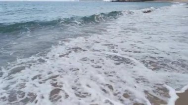 Gündüz sahnesi deniz yükseldiğinde kumlu kumsalda dalgalar hareket ederken