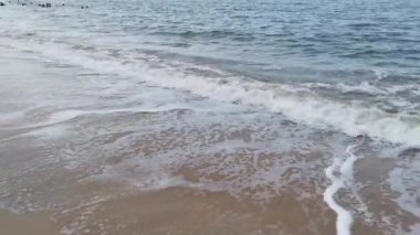 Gündüz sahnesi deniz yükseldiğinde kumlu kumsalda dalgalar hareket ederken