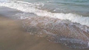 Gündüz sahnesi deniz yükseldiğinde kumlu kumsalda dalgalar hareket ederken