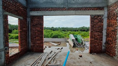 Bitmemiş inşaat binasının etrafında toplanan durgun yağmur suyu havuzu.