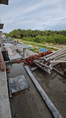 Bitmemiş inşaat binasının etrafında toplanan durgun yağmur suyu havuzu.