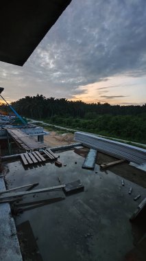 Bitmemiş inşaat binasının etrafında toplanan durgun yağmur suyu havuzu.