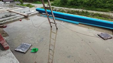 Bitmemiş inşaat binasının etrafında toplanan durgun yağmur suyu havuzu.